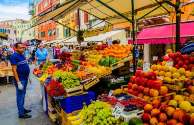 VENICE, ITALY, SEPTEMBER 20, 2015: crowds of tourists are passing through busy rio tera farsetti street which is full of restaurants and fruit vending stalls.