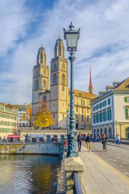 ZURİH, SWitzERLAND, ECTOBER 24, 2015: İnsanlar Zürih 'teki Grossmunster Katedrali önünde güneşli bir sonbahar gününde köprüden geçiyorlar