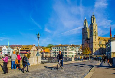 ZURİH, SWitzERLAND, ECTOBER 24, 2015: İnsanlar Zürih 'teki Grossmunster Katedrali önünde güneşli bir sonbahar gününde köprüden geçiyorlar