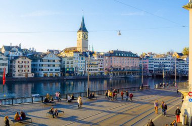 ZURICH, SWITZERLAND, OCTOBER 25, 2015: Zurich city center and Fraumunster in autumn in Switzerland. People are passing on a quay of limmat river