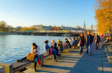 ZURİH, SWitzERLAND, ECTOBER 24, 2015: İnsanlar sonbahar öğleden sonra İsviçre 'de Zürih Gölü boyunca güneşli bir gezinti alanında yürüyorlar