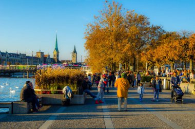 ZURİH, SWitzERLAND, ECTOBER 24, 2015: İnsanlar sonbahar öğleden sonra İsviçre 'de Zürih Gölü boyunca güneşli bir gezinti alanında yürüyorlar