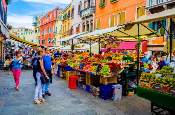 VENICE, ITALY, SEPTEMBER 20, 2015: crowds of tourists are passing through busy rio tera farsetti street which is full of restaurants and fruit vending stalls.