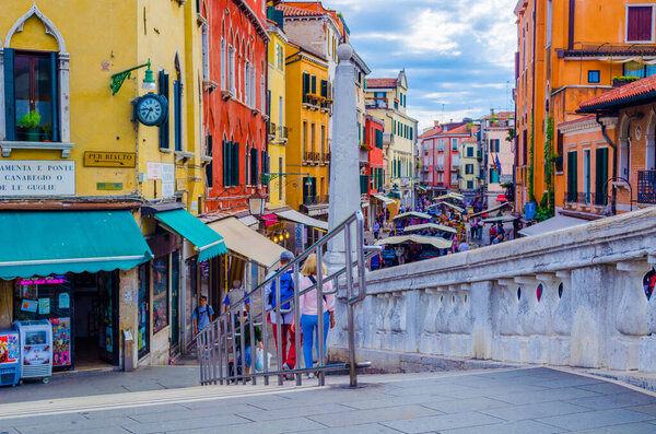 VENICE, ITALY, SEPTEMBER 21, 2015: crowds of tourists are passing through busy rio tera farsetti street which is full of restaurants and fruit vending stalls.