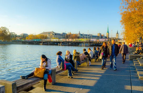 ZURİH, SWitzERLAND, ECTOBER 24, 2015: İnsanlar sonbahar öğleden sonra İsviçre 'de Zürih Gölü boyunca güneşli bir gezinti alanında yürüyorlar