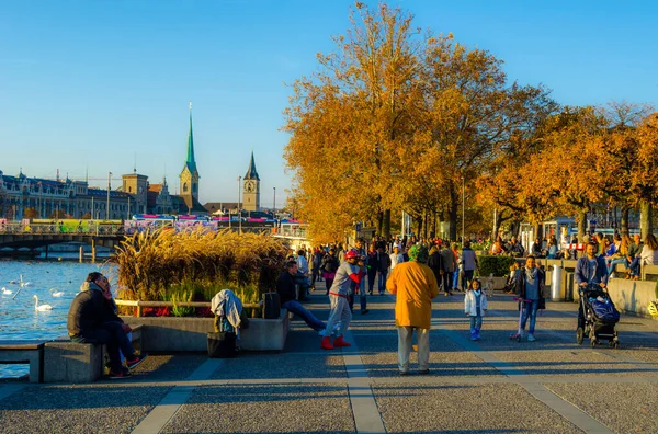 ZURİH, SWitzERLAND, ECTOBER 24, 2015: İnsanlar sonbahar öğleden sonra İsviçre 'de Zürih Gölü boyunca güneşli bir gezinti alanında yürüyorlar