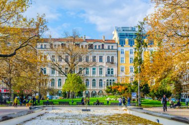 İnsanlar sonbaharda Sofya şehir merkezindeki bir parkta yürüyorlar.