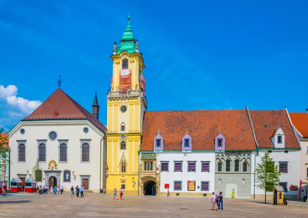 İnsanlar Bratislava 'nın ana meydanındaki belediye binasının önünde geziniyorlar (hlavne name mestie)