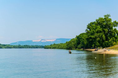 İnsanlar Macaristan 'daki Danube nehrinin kıvrımlarındaki kumlu sahilde güneşli bir günün tadını çıkarıyorlar.