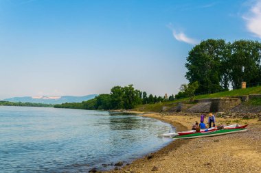 İnsanlar Macaristan 'daki Danube nehrinin kıvrımlarındaki kumlu sahilde güneşli bir günün tadını çıkarıyorlar.