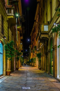 İtalya 'nın Milano şehrinde aydınlık dar bir caddenin gece görüşü.