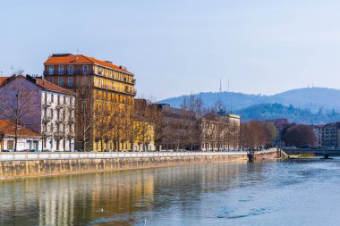 İtalyan Torino şehrindeki Dora Riparia nehrinin nehir kenarına uzanan tarihi binalar..