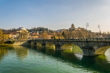 people are crossing a bridge over river po in front of the Gran Madre di Dio Church in Turin.