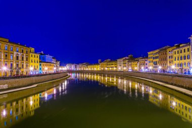 İtalyan şehri Pisa 'nın tarihi merkezinde Arno nehri boyunca uzanan tarihi binaların gece manzarası.