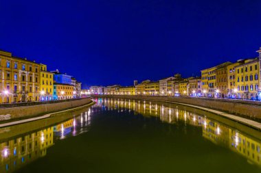 İtalyan şehri Pisa 'nın tarihi merkezinde Arno nehri boyunca uzanan tarihi binaların gece manzarası.