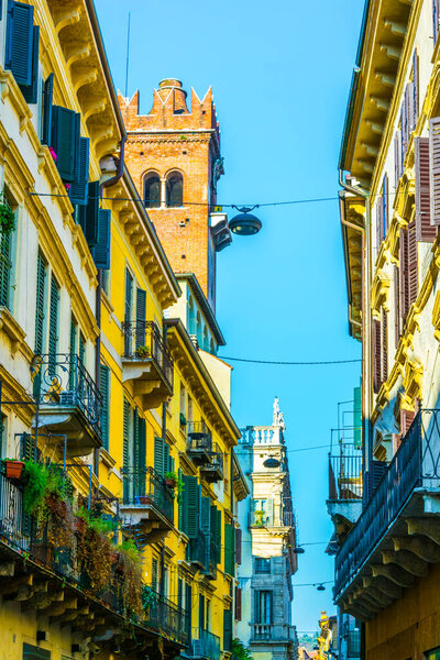 View of a narrow street overlooked by torre die lamberti in Verona, Italy