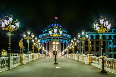 Skopje 'deki Dışişleri Bakanlığı ve Mali Polis Departmanı' na giden köprünün gece görüşü Macedonia ve Fyrom tarihi ile ilgili birçok heykelle süslenmiştir..