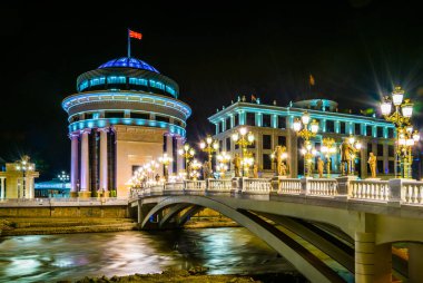 Skopje 'deki Dışişleri Bakanlığı ve Mali Polis Departmanı' na giden köprünün gece görüşü Macedonia ve Fyrom tarihi ile ilgili birçok heykelle süslenmiştir..