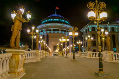 Skopje 'deki Dışişleri Bakanlığı ve Mali Polis Departmanı' na giden köprünün gece görüşü Macedonia ve Fyrom tarihi ile ilgili birçok heykelle süslenmiştir..