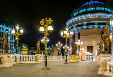 Skopje 'deki Dışişleri Bakanlığı ve Mali Polis Departmanı' na giden köprünün gece görüşü Macedonia ve Fyrom tarihi ile ilgili birçok heykelle süslenmiştir..