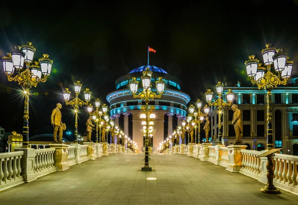 Skopje 'deki Dışişleri Bakanlığı ve Mali Polis Departmanı' na giden köprünün gece görüşü Macedonia ve Fyrom tarihi ile ilgili birçok heykelle süslenmiştir..