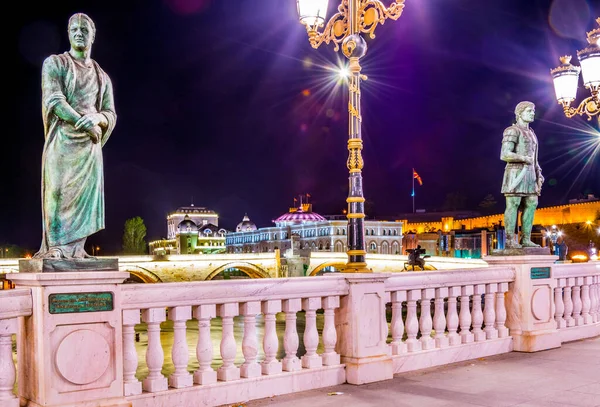 Ünlü taş köprünün arkasındaki Skopje 'deki ulusal tiyatronun gece manzarası