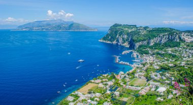 İtalyan tatil adası Capri 'sinin havadan görünüşü iki tepenin üzerine ve aralarında iki küçük şehre yayılmış güzel doğayı birleştiriyor.