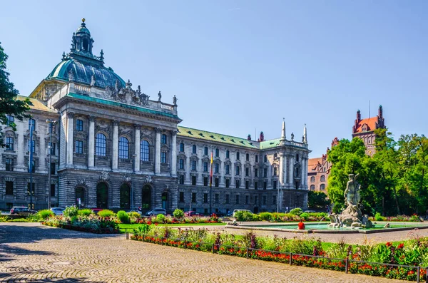 View of langericht court in german city munich hidden behind magnificent fountain.