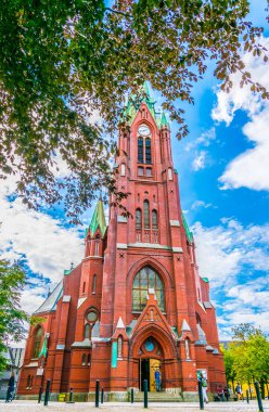 People are passing by red Johanneskirken church in the norwegian city Bergen