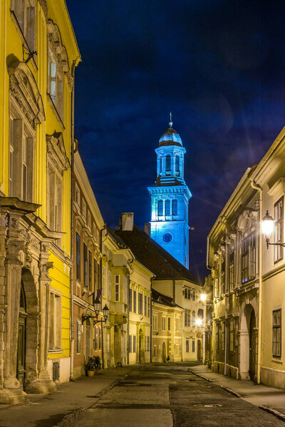 Narrow street in the old town of Sopron Templom utca street with an evangelic church at the very end during night, Hungary