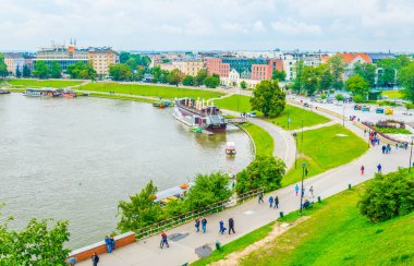 İnsanlar Polonya 'daki Krakow / Cracow' daki Wistula kalesinin altındaki Vistula nehri kıyısında dinleniyorlar..