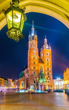 Saint Mary Kilisesi 'nin Polonya şehri Krakow / Krakow' daki gece manzarası Sukiennice pazar yerinin kemerinden (Kumaş Salonu, Drapers 'Hall)
