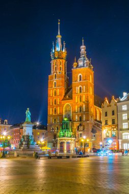 St. Mary Kilisesi 'nin gece manzarası. Polonyalı Cracow / Krakow kentindeki Rynek parlayan ana meydanında Adam Mickiewicz' in heykeli var..