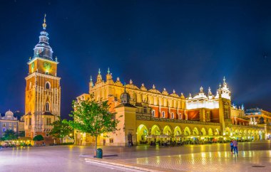 Polonyalı şehir Krakow / Krakow 'da belediye binası ve sukiennice pazar yeri olan Rynek parlayan ana meydanının gece manzarası.