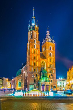 St. Mary Kilisesi 'nin gece manzarası. Polonyalı Cracow / Krakow kentindeki Rynek parlayan ana meydanında Adam Mickiewicz' in heykeli var..
