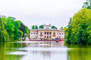 a boat is approaching the Palace on the Water, also called Lazienki Palace or Palace on the Isle in Lazienki Royal Park, Warsaw, Poland 