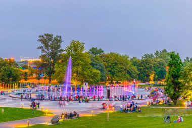 İnsanlar Polonya, Varşova 'daki aydınlık çeşmeleri görmek için Multimedia Fountain Park' ın etrafında toplanıyor..