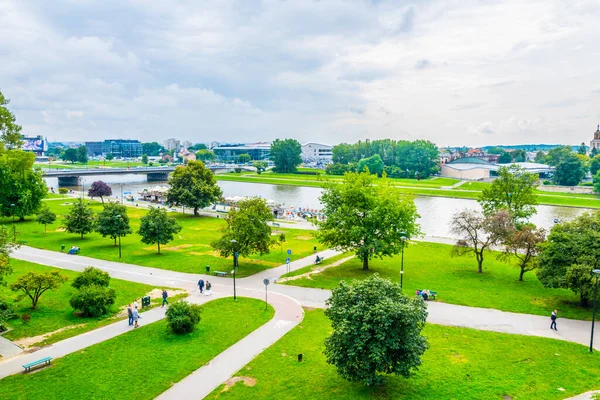 İnsanlar Polonya 'daki Krakow / Cracow' daki Wistula kalesinin altındaki Vistula nehri kıyısında dinleniyorlar..