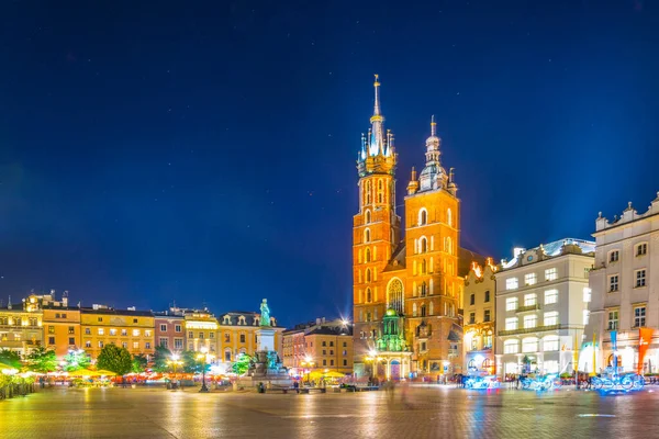 St. Mary Kilisesi 'nin gece manzarası. Polonyalı Cracow / Krakow kentindeki Rynek parlayan ana meydanında Adam Mickiewicz' in heykeli var..
