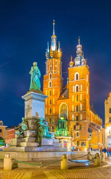 St. Mary Kilisesi 'nin gece manzarası. Polonyalı Cracow / Krakow kentindeki Rynek parlayan ana meydanında Adam Mickiewicz' in heykeli var..