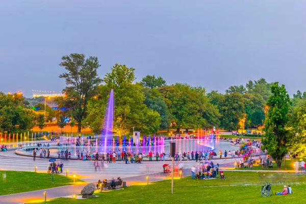 İnsanlar Polonya, Varşova 'daki aydınlık çeşmeleri görmek için Multimedia Fountain Park' ın etrafında toplanıyor..