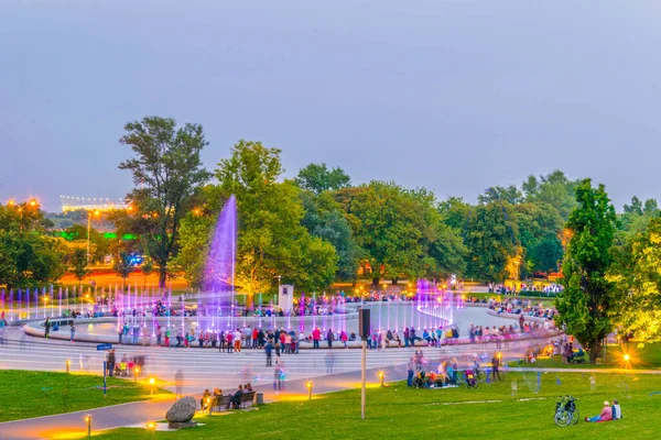 İnsanlar Polonya, Varşova 'daki aydınlık çeşmeleri görmek için Multimedia Fountain Park' ın etrafında toplanıyor..