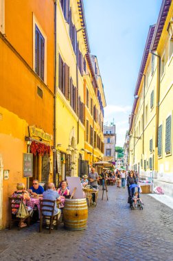 people are strollin through narrow street of trastevere district in italian capital rome, which ic local center of nighlife, tourist and delicious cuisine.