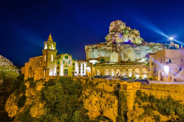 İtalyan şehrinin çatılarının gece manzarası. Matera, San Pietro mağarası ve Madonna de Idris kilisesi.