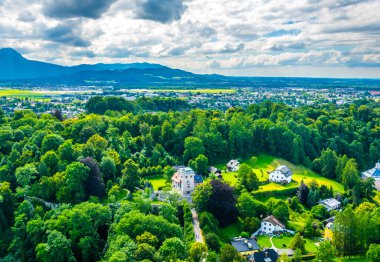 Avusturya 'nın Salzburg kentinde bir banliyö manzarası. Aile evleri ormanlar, çayırlar ve tepelerle çevrili.