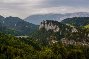 Krauselklause, Polleroswand 'ın önündeki demiryolunu çevreleyen dağ manzarasıyla donatır. Arka planda karlı Rax dağ sırası var. Breitenstein am Semmering, Aşağı Avusturya, Avusturya