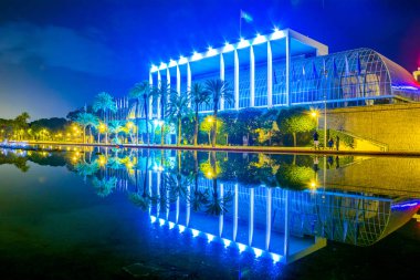 Palau de la musica de valencia konser salonunun gece boyunca bir gölete yansıyan görüntüsü.