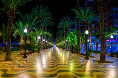 Night view of illuminated promenade in spanish city Alicante, which is streteched alongside the mediterranean sea.