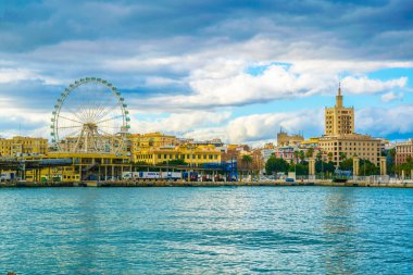 view of a ferris wheel situated on a waterfront of the port of malaga in spain