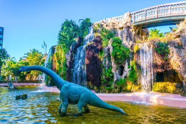 Cadiz 'deki genov parkında yapay bir kayanın önündeki bir dinozor heykeli.